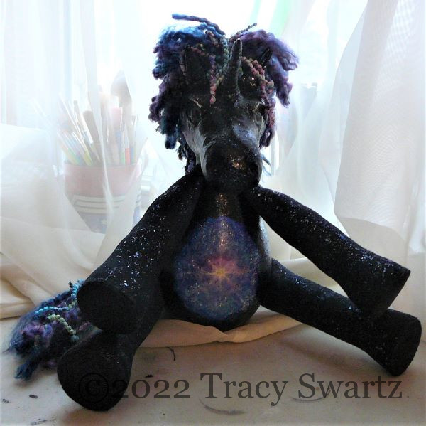 Front view of a dark unicorn made from hard shell gourds and mixed media with a scene from the Universe on it's belly